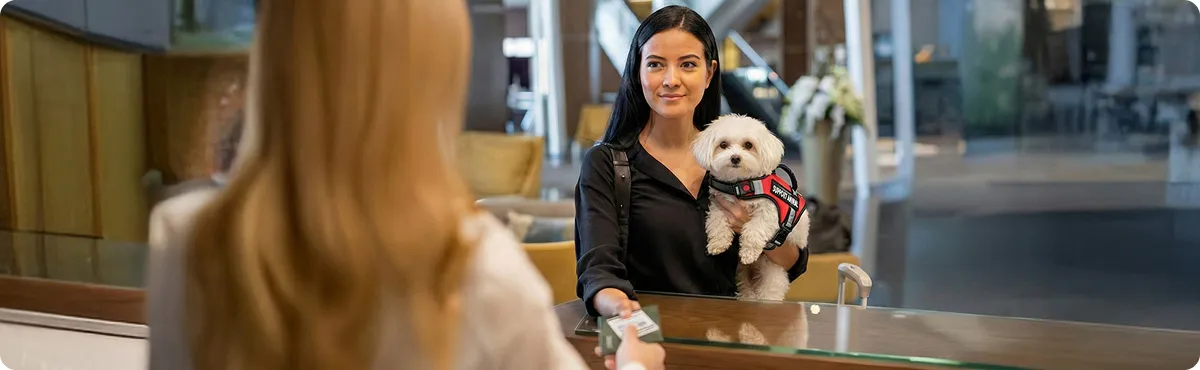 Woman with service animal checking in at hotel reception desk